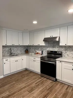 a kitchen with white cabinets and black appliances at Calm Retreat in Plainview