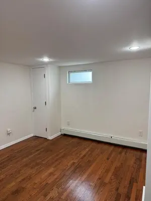 an empty room with white walls and wood floors at Calm Retreat in Plainview
