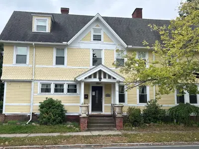 a yellow house with a black roof at Historic Springfield Home in Springfield