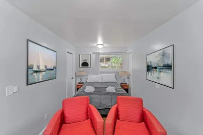 a bedroom with a bed and two red chairs at The Main Lineup 3 - All Star Baseball Rentals in Oneonta