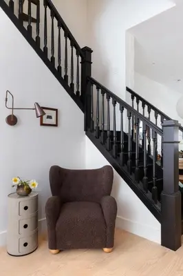a living room with a chair under a staircase at Massive NYC Brownstone wPatio in New York