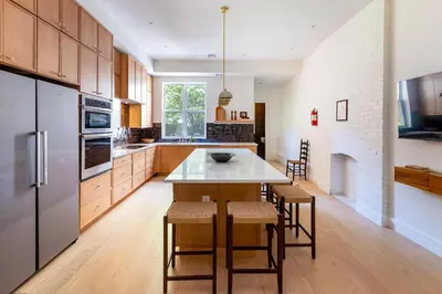 a kitchen with wooden cabinets and a table with chairs at Massive NYC Brownstone wPatio in New York