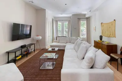 a living room with a white couch and a tv at Massive NYC Brownstone wPatio in New York