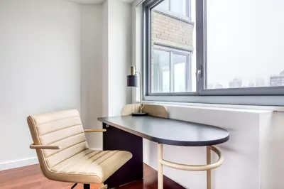 a desk and a chair in a room with a window at Blueground Murray Hill balcony nr East River NYC-720 in New York