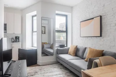 a living room with a couch and a kitchen at Blueground Alphabet City view nr Tompkins Sq Park NYC-1884 in New York