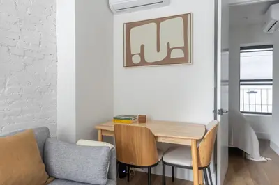 a living room with a wooden table and a chair at Blueground Alphabet City view nr Tompkins Sq Park NYC-1884 in New York