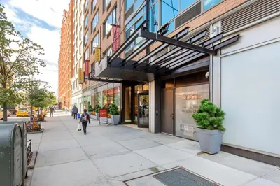 a woman walking down a sidewalk in front of a store at Blueground Chelsea rooftop nr Highline NYC-369 in New York