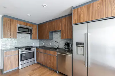 a kitchen with stainless steel appliances and wooden cabinets at Blueground Clinton Hill rooftop nr Fort Greene Park NYC-1979 in Brooklyn