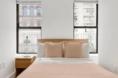 a bedroom with a bed and two large windows at Blueground Midtown East view nr UN Plaza NYC-2040 in New York