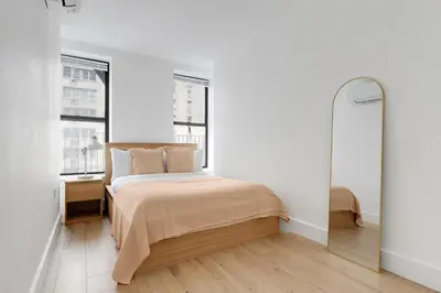 a white bedroom with a bed and two windows at Blueground Midtown East view nr UN Plaza NYC-2040 in New York
