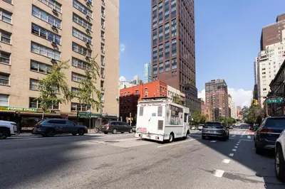 a food truck is driving down a busy city street at Blueground Midtown East view nr UN Plaza NYC-2040 in New York