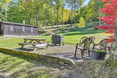 a picnic table and benches in a park with a cabin at Ice Fish, Snowshoe and Ski Group Getaway in Summit in Summit