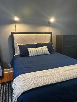 a bedroom with a blue bed with two lamps at Modern Comfort 1BR in Jersey City in Jersey City