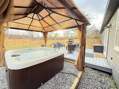 a hot tub with an umbrella on a patio at Vibing Hudson Retreat Pet-Friendly w Hot Tub in Hudson