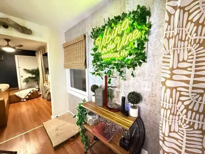 a living room with a green sign on a wall at Vibing Hudson Retreat Pet-Friendly w Hot Tub in Hudson