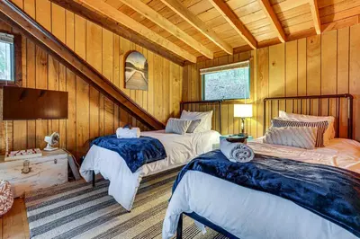 two beds in a room with wooden walls at Less Than 1 Mi to Lake Cabin with Hot Tub in Greentown! in Greentown