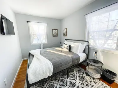 a bedroom with a bed and a tv and a window at Sparkling Saratoga 3BR home near Track and SPAC Dogs in Saratoga Springs