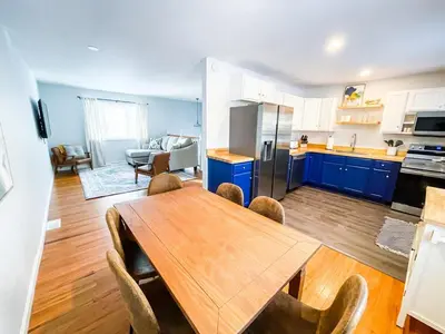 a kitchen and dining room with a wooden table and blue cabinets at Sparkling Saratoga 3BR home near Track and SPAC Dogs in Saratoga Springs