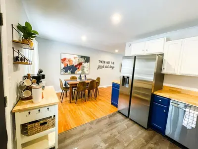 a kitchen and dining room with a table and a refrigerator at Sparkling Saratoga 3BR home near Track and SPAC Dogs in Saratoga Springs