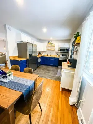 a kitchen with blue cabinets and a wooden table at Sparkling Saratoga 3BR home near Track and SPAC Dogs in Saratoga Springs