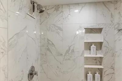 a bathroom with a shower with white marble tiles at Cozy Log Cabin Near Mt Snow Views, Modern Comfort in Wilmington