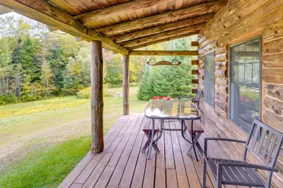 a wooden deck with a table and chairs on it at Cozy Log Cabin Near Mt Snow Views, Modern Comfort in Wilmington
