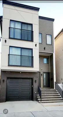 a house with two garage doors and a building at Luxury 3BR Retreat Near NYC in Newark