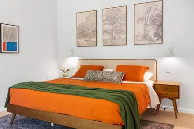 a bedroom with an orange bed with four pictures on the wall at Modern Family Retreat in the Catskills Wilderness in Round Top