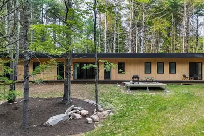 a house in the woods with a bench and a picnic table at Modern Family Retreat in the Catskills Wilderness in Round Top