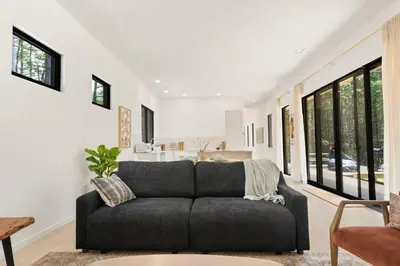 a living room with a gray couch and windows at Modern Family Retreat in the Catskills Wilderness in Round Top