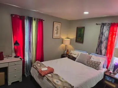 a bedroom with a large bed with red curtains at Hidden and comfortable home away from home in Manchester