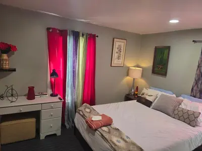 a bedroom with a bed and a desk and red curtains at Hidden and comfortable home away from home in Manchester