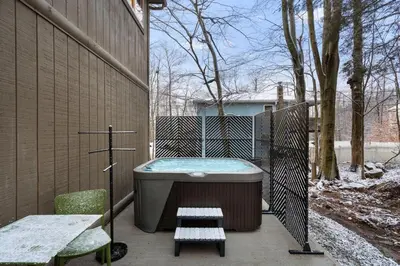a bath tub sitting next to a fence with a bench at Cozy Poconos Retreat - pool table, hot tub, fire pit in Tobyhanna