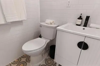 a white bathroom with a toilet and a sink at Spacious 3Bedroom with AC near McCarren Park Brooklyn Stay in Brooklyn