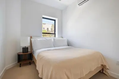 a white bedroom with a bed and a window at Blueground Greenpoint view nr McGolrick Park NYC-2071 in Brooklyn