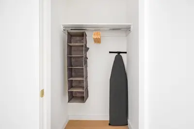 a closet with a black umbrella and shelves at Blueground Greenpoint view nr McGolrick Park NYC-2071 in Brooklyn