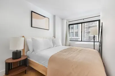 a white bedroom with a bed and a window at Blueground Midtown East rooftop nr Grand Central NYC-2069 in New York