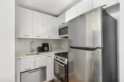a kitchen with white cabinets and a stainless steel refrigerator at Blueground Midtown East rooftop nr Grand Central NYC-2069 in New York