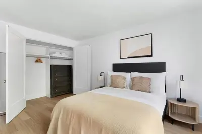 a white bedroom with a large bed with white walls at Blueground Yorkville pool nr Carl Schurz Park NYC-2093 in New York