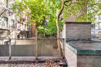 a fence on a street with trees and buildings at Blueground Yorkville pool nr Carl Schurz Park NYC-2093 in New York
