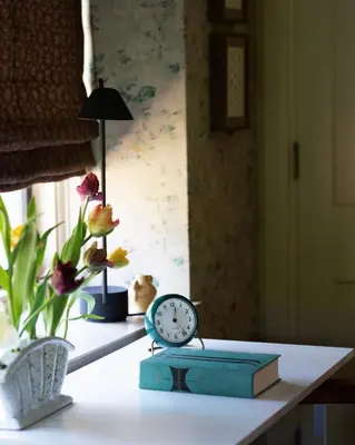 a clock sitting on a table with a book and flowers at Argyll House by Boutique Litchfield Escape Villa in Harwinton