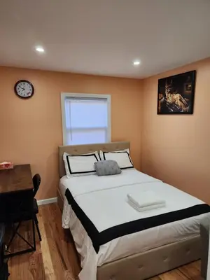 a bedroom with a bed and a clock on the wall at Unique Home Rentals For Professionals in Baychester