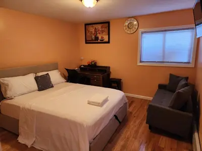 a bedroom with a bed and a chair and a clock at Unique Home Rentals For Professionals in Baychester