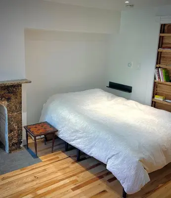 a bedroom with a bed and a table next to a fireplace at Studio Apartment with Garden Jersey City in Jersey City