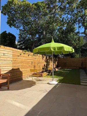 a green umbrella in a yard with chairs and a fence at Studio Apartment with Garden Jersey City in Jersey City
