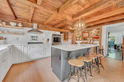 a kitchen with white cabinets and wooden ceilings at A perfect couples fall getaway in Hawley