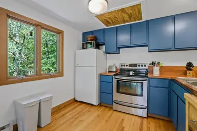 a kitchen with blue cabinets and a white refrigerator at House Under The Cliff in New Paltz