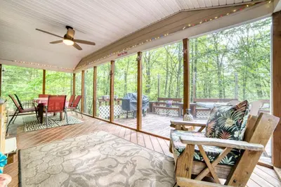 a screened in porch with a ceiling fan and chairs at 1mi to Lake Wallenpaupack | Firepit | Pet Friendly in Greentown