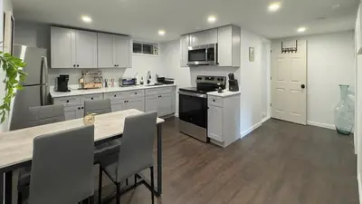 a kitchen with white cabinets and a table with chairs at Modern Apartment Near Tweed -Yale -New Haven in New Haven
