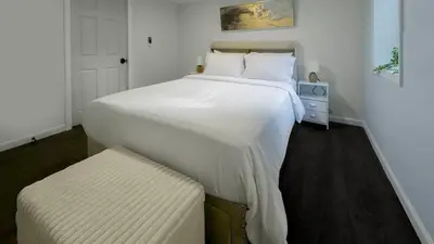 a bedroom with a large white bed and a stool at Modern Apartment Near Tweed -Yale -New Haven in New Haven
